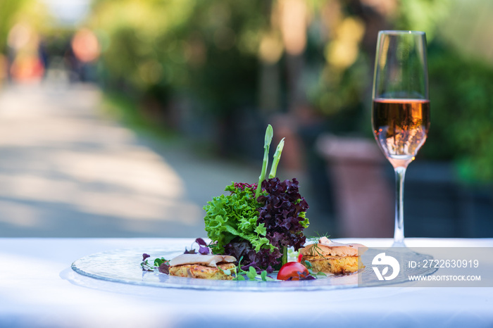 Fine Dining Salat mit einem Glas Champagner auf einer Terrasse