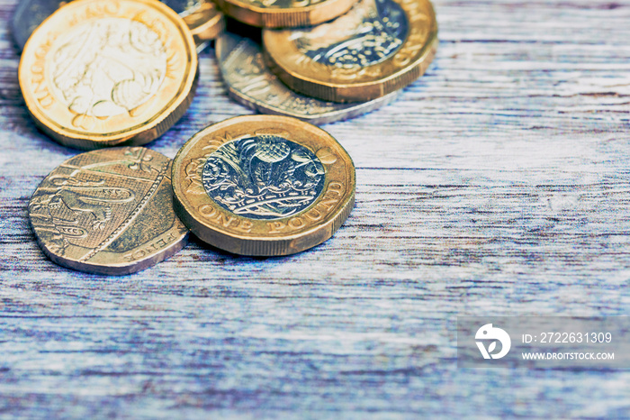 macro of British one pound sterling coins in cold color style on wooden surface