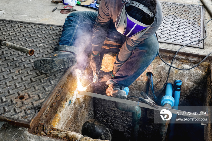 worker repairing pipes on road  welding