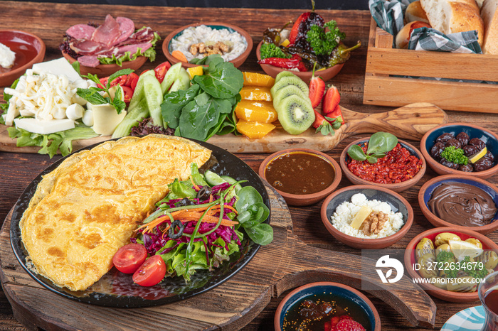 Traditional Turkish Breakfast served with traditional turkish tea on wood table. Breakfast or brunch table filled with all sorts of delicious delicatessen. Turkish name; Serpme Kahvalti.