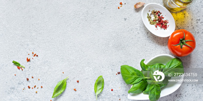 Fresh vegetables and herbs with spices on a gray background. Food background. Flatlay of ripe tomato, fresh basil leaves, garlic and spices, healthy food concept, copy space.