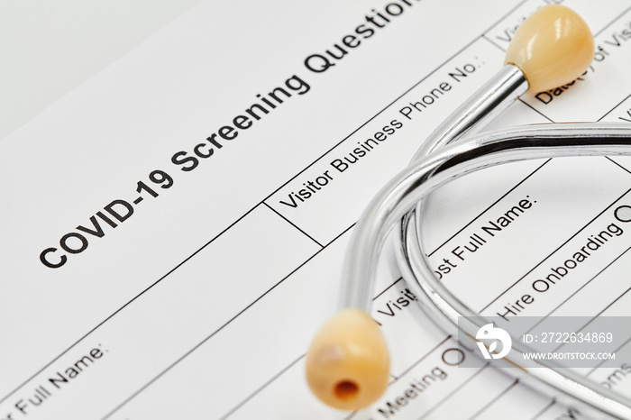 COVID-19 Screening questionnaire form with stethoscope on it. Closeup.