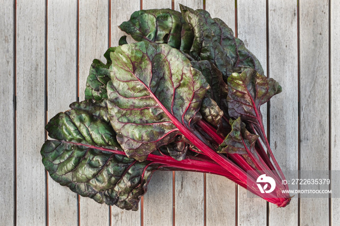 Freshly harvested Swiss chard laying on a wooden table outside