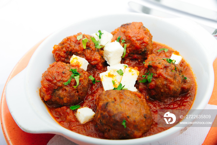 Spicy bifteki, frikadelle or frikkadel meatballs with minced beef and lamb with pita bread, tzatziki dip, vegetables salad and French fries. Greek meatballs keftedes or Keftedakia.