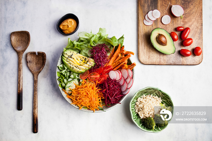 Rainbow detox bowl. Raw vegetable salad with quinoa, broccoli, carrot, sweet potato, tomatoes, avocados and lettuce.