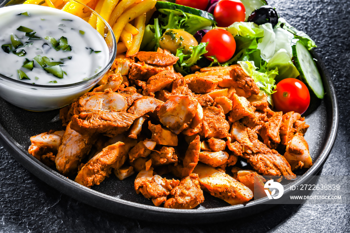 Kebab served with french fries, vegetable salad and tzatziki