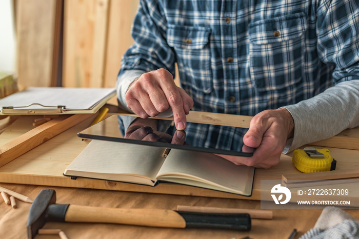 Carpenter using digital tablet to complete project to do list