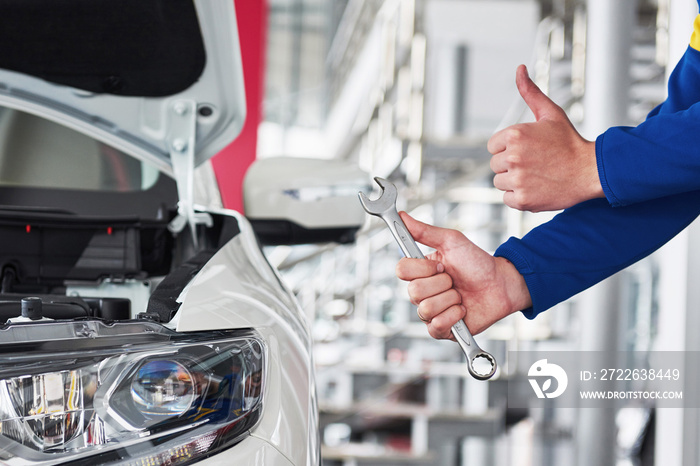 Hands of car mechanic with wrench in garage.