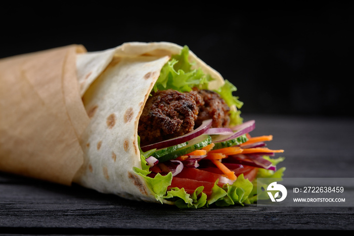 Tasty doner kebabs with fresh salad trimmings and shaved roasted meat served in tortilla wraps on brown paper as a takeaway snack