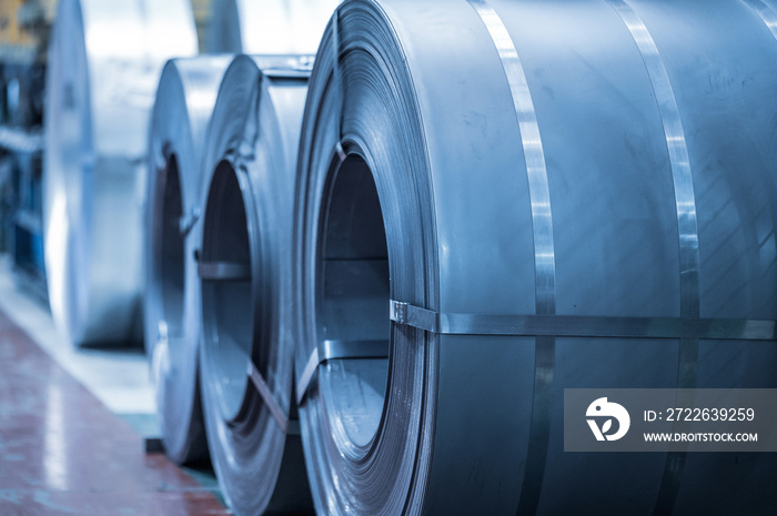 Industrial background. Big size steel coil stored inside industrial warehouse, blue toned image .