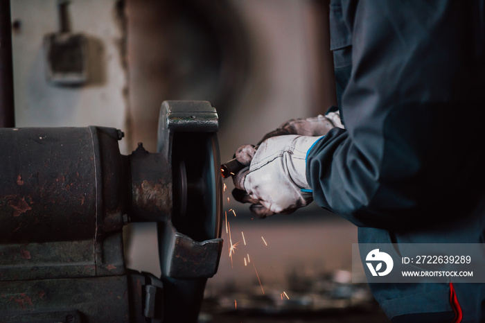 Close up of a man in gloves polishing iron materials in an industry