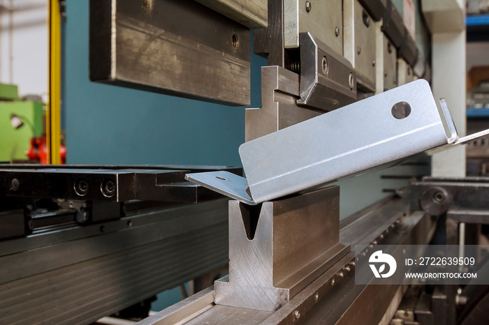 Bending sheet metal on a hydraulic machine at the factory. Bend tools, press brake punch and die. Close-up.