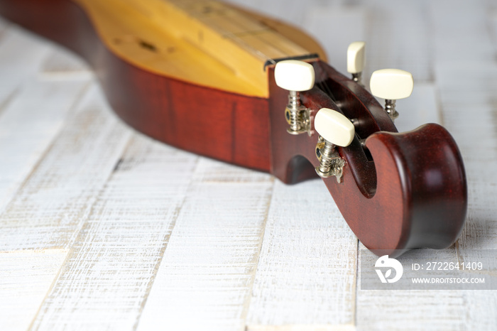 Appalachian mountain dulcimer musical instrument on a rustic white wooden background