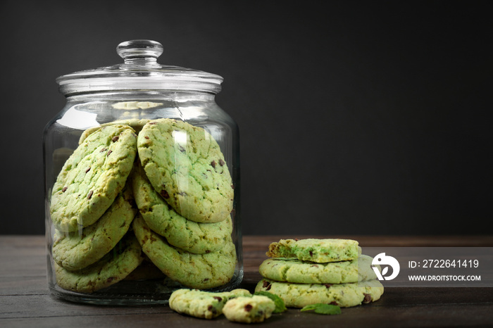 Jar with mint chocolate chip cookies on wooden table