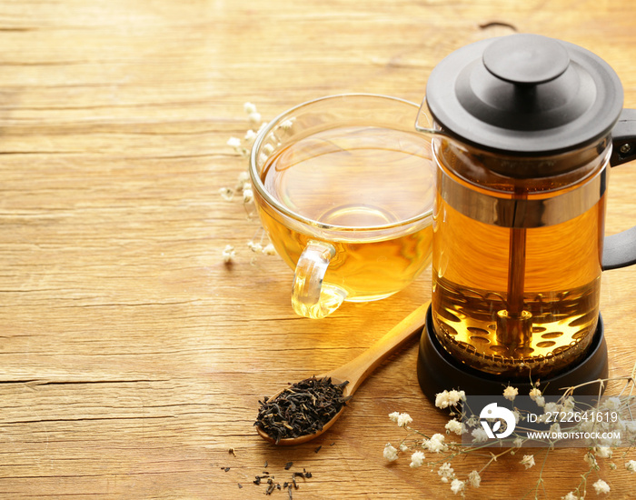 kettle French press with fragrant tea on a wooden table