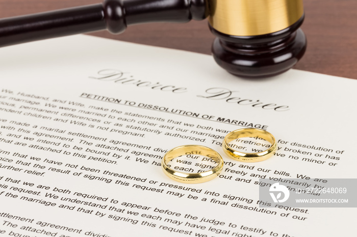 Wooden judge gavel, golden rings, and divorce decree; document is mock-up