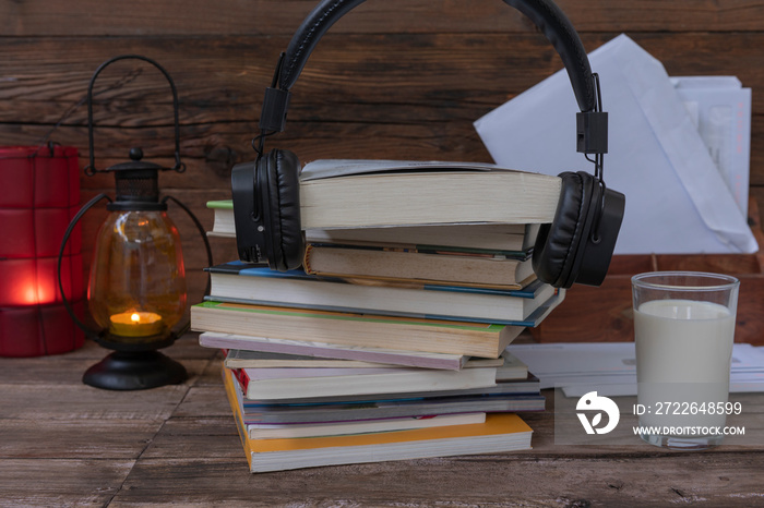 Auriculares y libros junto a un vaso de leche.