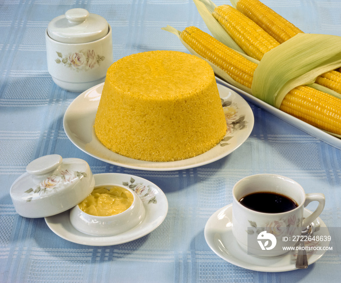 Corn couscous at the table with a cup of coffee and boiled corn cobs. Typical food from the northeast region of Brazil.