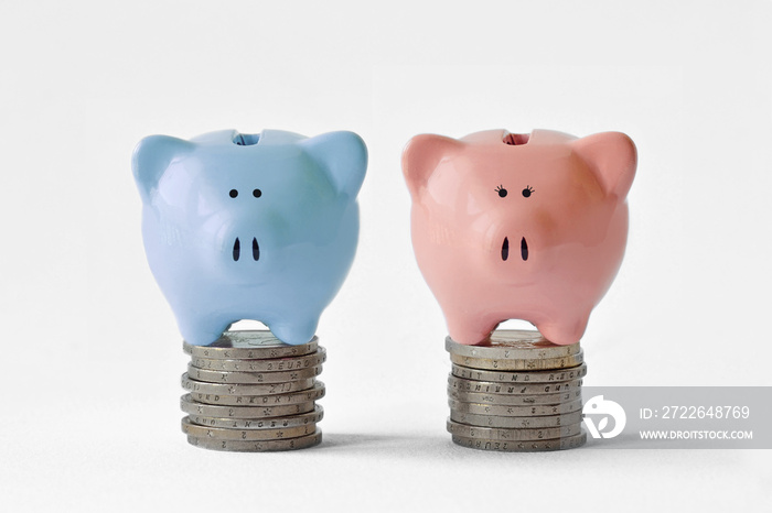 Blue and pink piggy bank on stack of coins - Gender pay equality concept