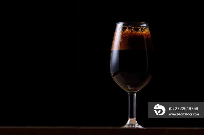 Dark beer in a glass on a dark background.