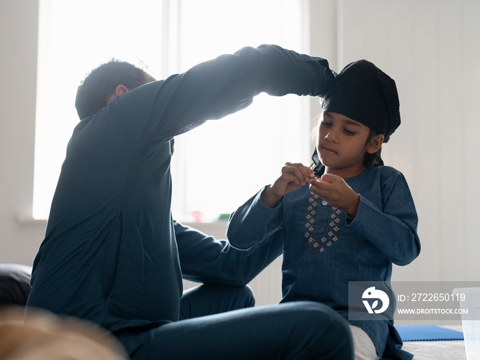 Father wrapping turban around son’s head (6-7)