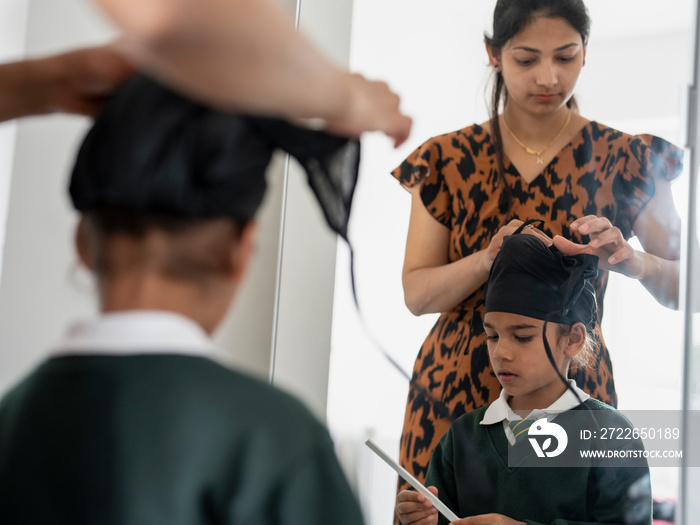 Mother wrapping traditional turban on son’s (6-7) head