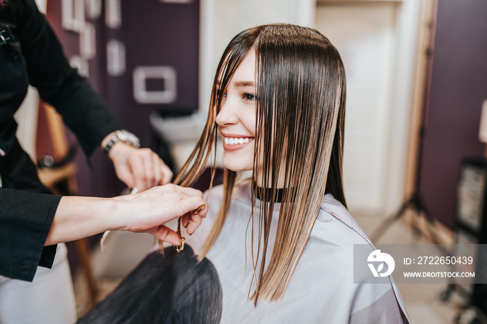 Beautiful young woman getting her haircut by a hairstylist at a beauty salon.