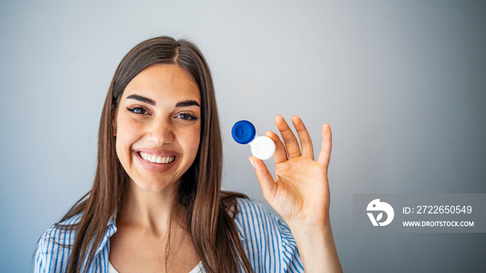 Woman holding plastic container with contact lenses, indoors. Young woman holds case for contact lenses.  Woman holding contact eye lenses container