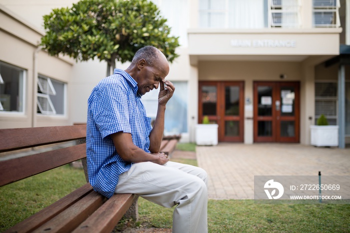 Sad senior man sitting on wooden bench