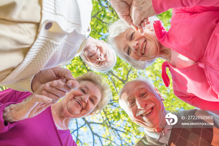 Upward view of two elder couples smiling to the camera. Happines