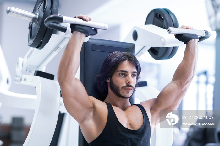 Bodybuilder working out with shoulder press machine