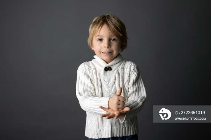 Cute little toddler boy, showing HELP gesture in sign language on gray background, isolated image, child showing hand sings