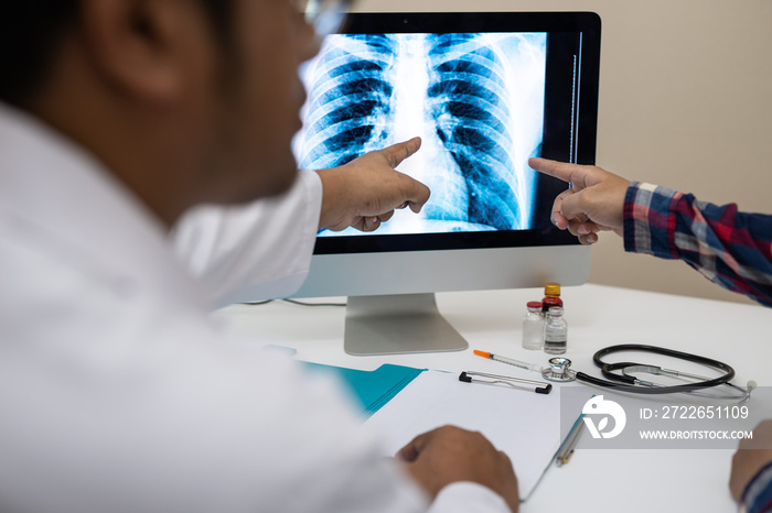 Professional doctor and radiologist giving a consultation to his patient, He pointed to the results of x-ray at the computer screen..