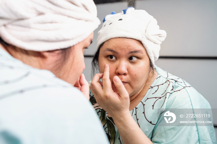 Plus size female examining her skin in the mirror