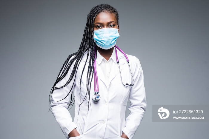 Portrait of african female nurse wearing mask and hair net on gray background