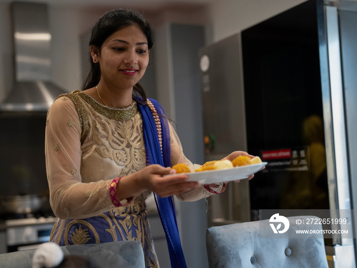 Young woman in traditional clothing carrying food on plate