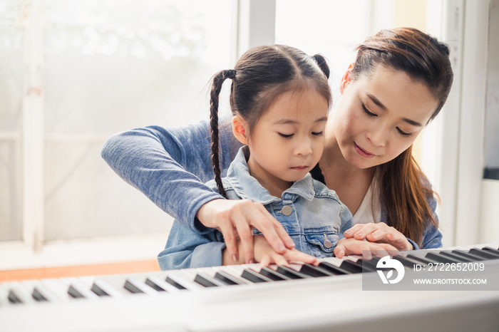 Asian young pianist teacher teaching girl kid student to play piano, music education concept