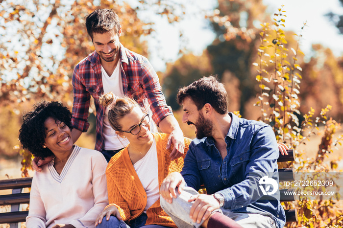 Group of young people having fun outdoors on park bench