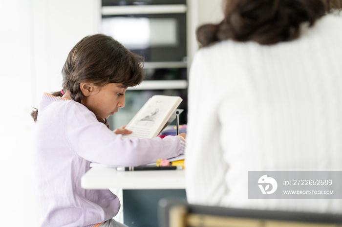 Little girl doing homework with sister