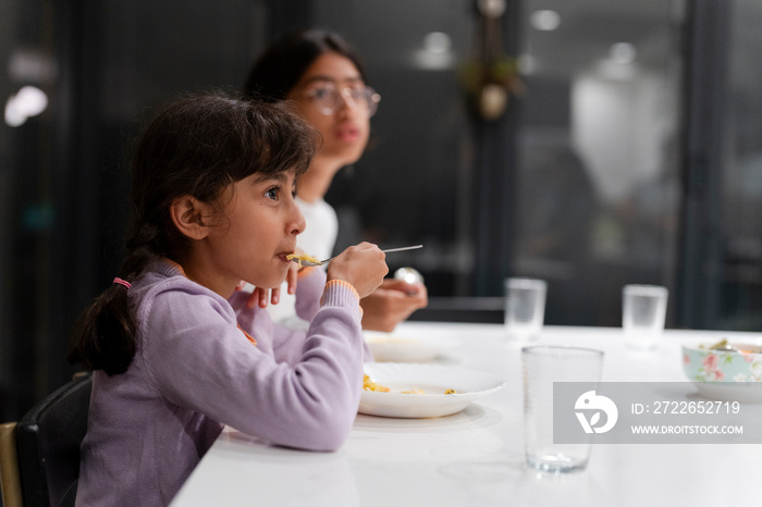 Sisters eating meal at table