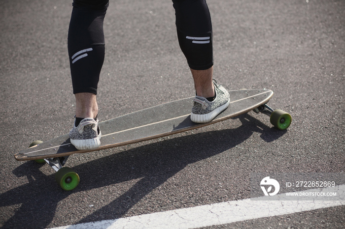 Man riding on longboard skate on road through forest or city. Man’s legs on skateboard or longboard.