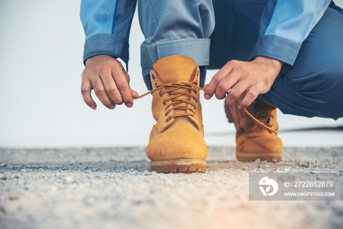 Man kneel down and tie shoes industry boots for worker. Close up shot of man hands tied shoestring for his construction brown boots.  Close up man hands tie up shoes for footwear concept.