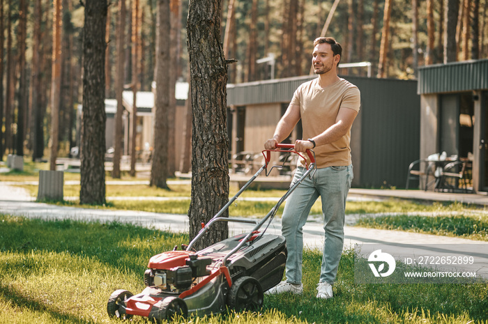 Young man standing with lawn mower