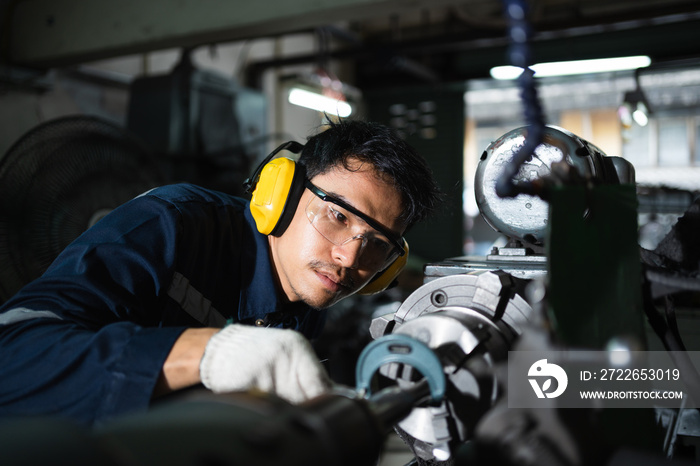 Factory mechanics in safety suits using a micrometer to measure outside diameter metal after grinding in the factory.