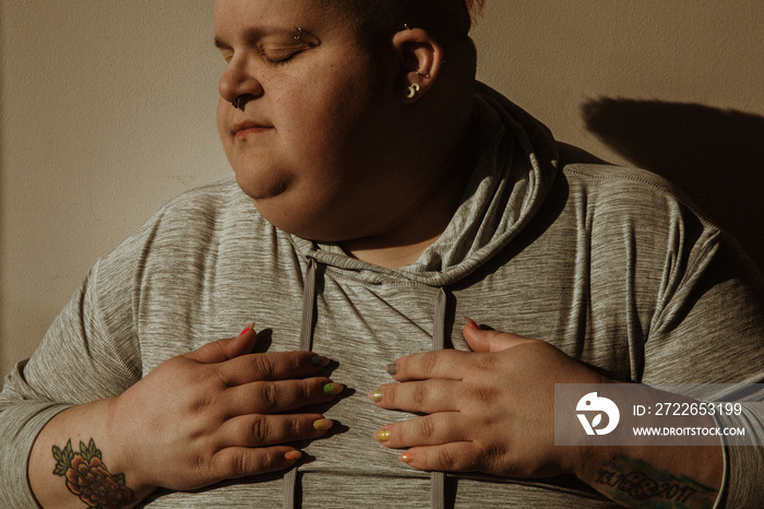 closeup portrait of a plus size woman hands on chest