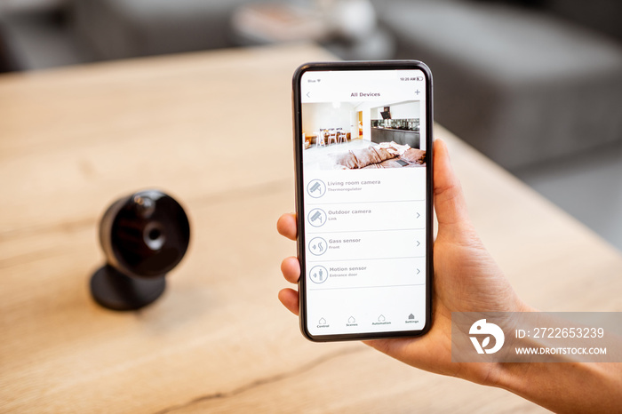 Close-up on a smart phone with launched security application and IP camera at the table. Home video surveillance concept
