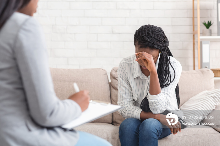 Depressed woman sitting on couch at psychotherapy session in coucellor’s office