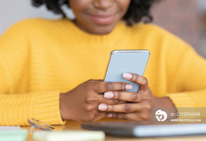 Cropped of black young woman holding smartphone