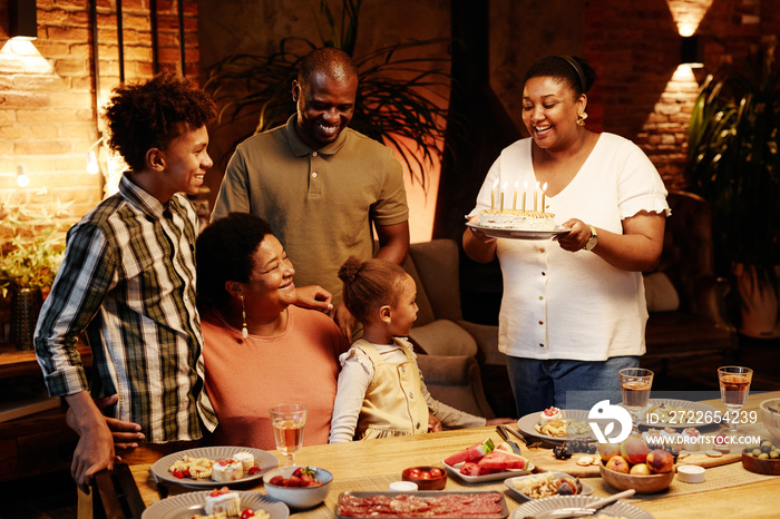 Cozy warm toned portrait of happy African-American family celebrating Birthday together indoors at evening