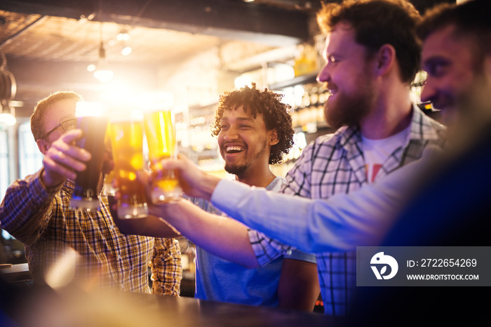 Handsome smiling young afro-american man clinking beer glasses in the pub.